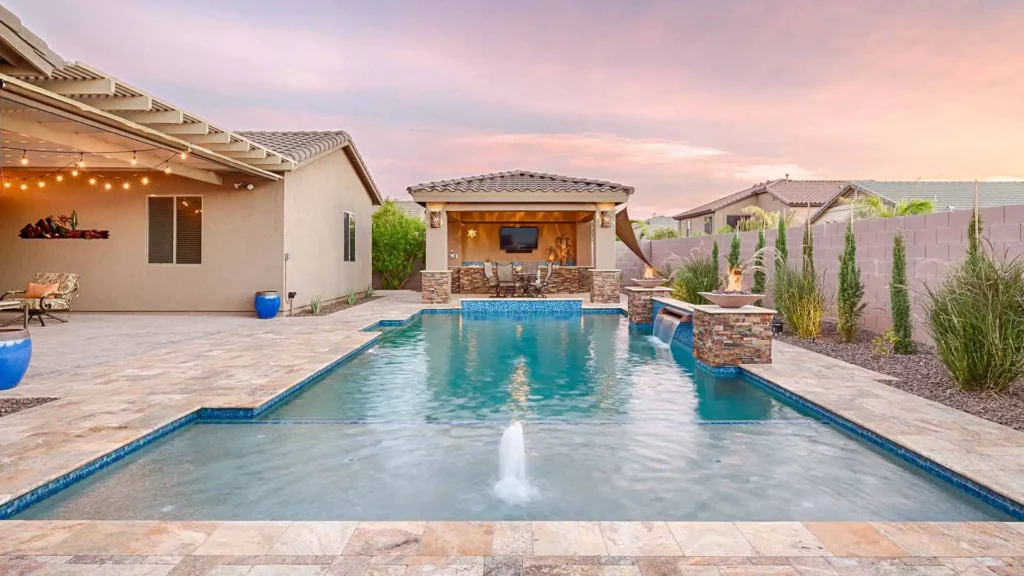Exquisite backyard oasis with a serene pool, luxurious covered patio, and elegant fire-water features under a warm sky