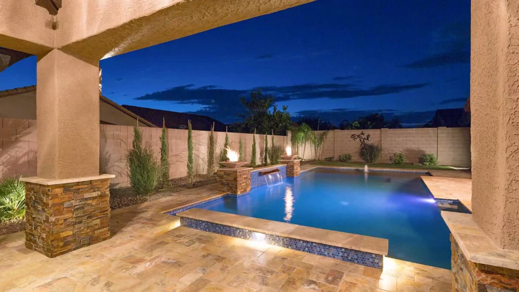A serene and lavish backyard oasis at twilight, featuring a luminous pool, exquisite water features, and ambient fire bowls
