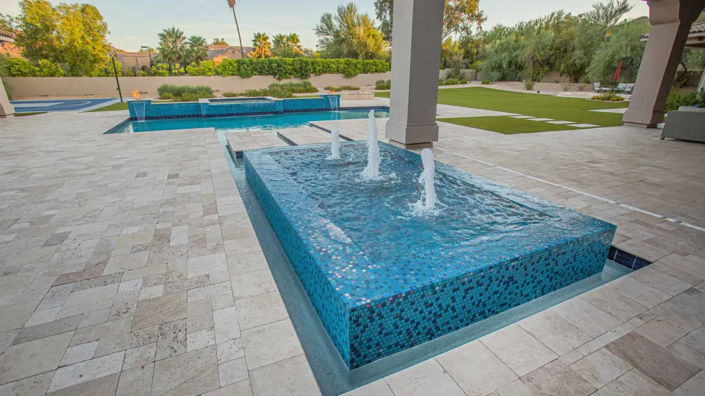 Sumptuous travertine patio surrounding a tranquil azure pool and a dazzling mosaic fountain