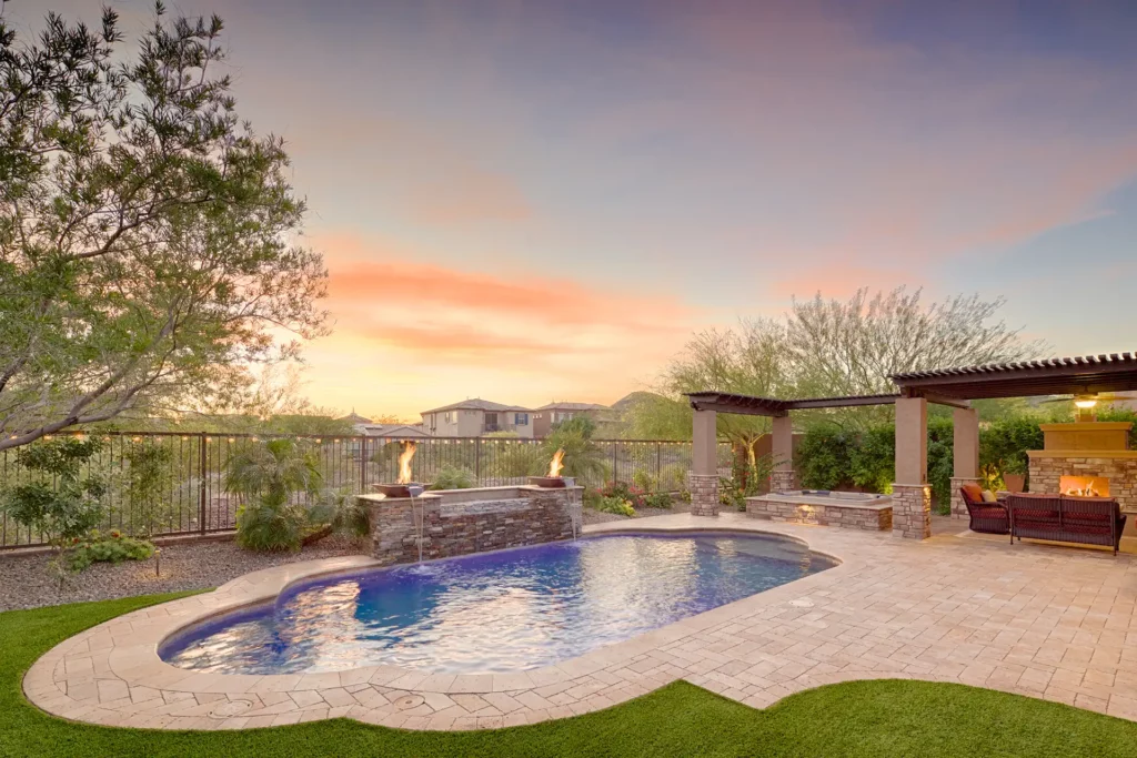 Exquisite backyard oasis featuring a tranquil pool, elegant patio, and glowing fire and water features under a vibrant sunset sky