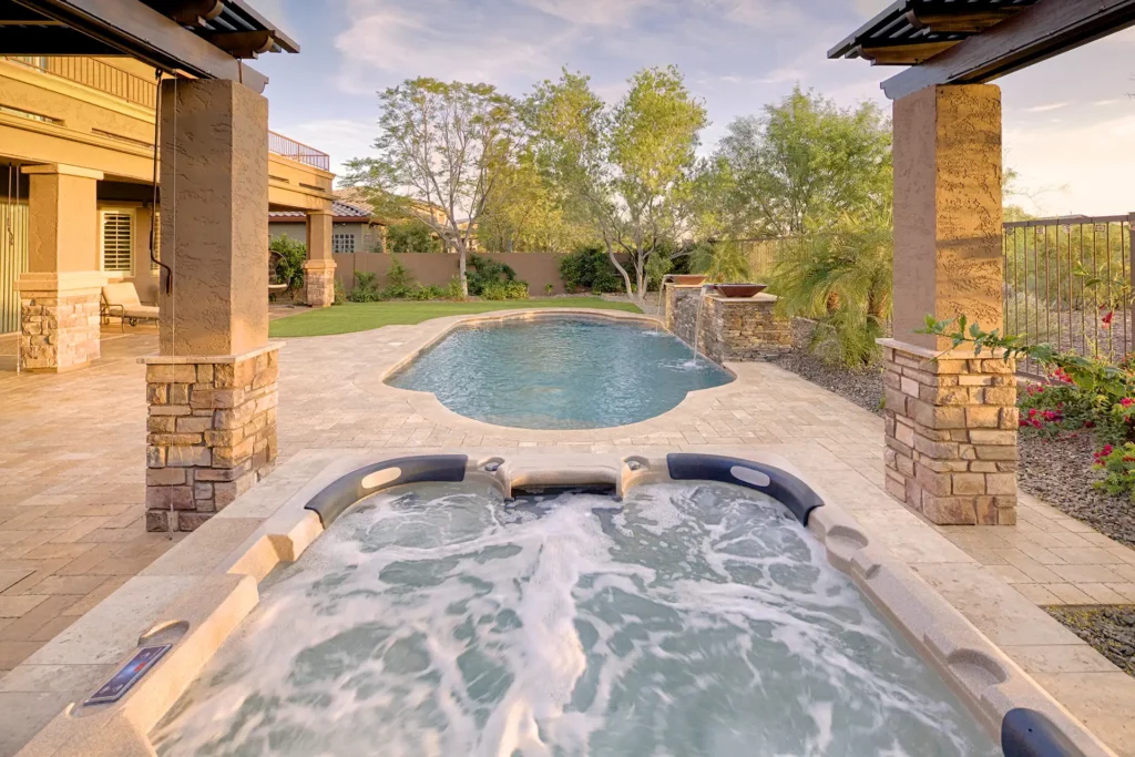 Tranquil desert haven showcasing an opulent swimming pool and a rejuvenating spa, amidst exquisite stone work and vibrant landscaping