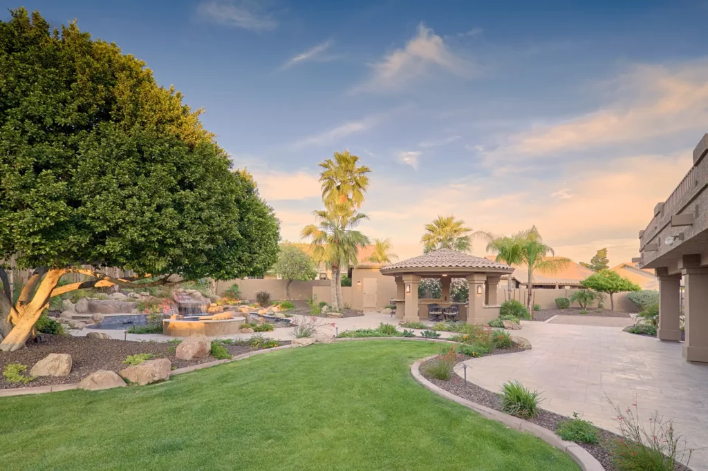 An exquisite Arizona backyard oasis featuring a serene waterfall pool, vibrant landscaping, and elegant gazebo