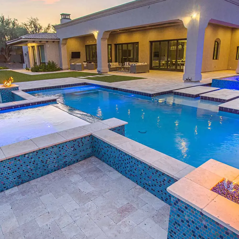 Serene backyard oasis featuring a sumptuous pool and spa, illuminated by exquisite fire and water features at dusk